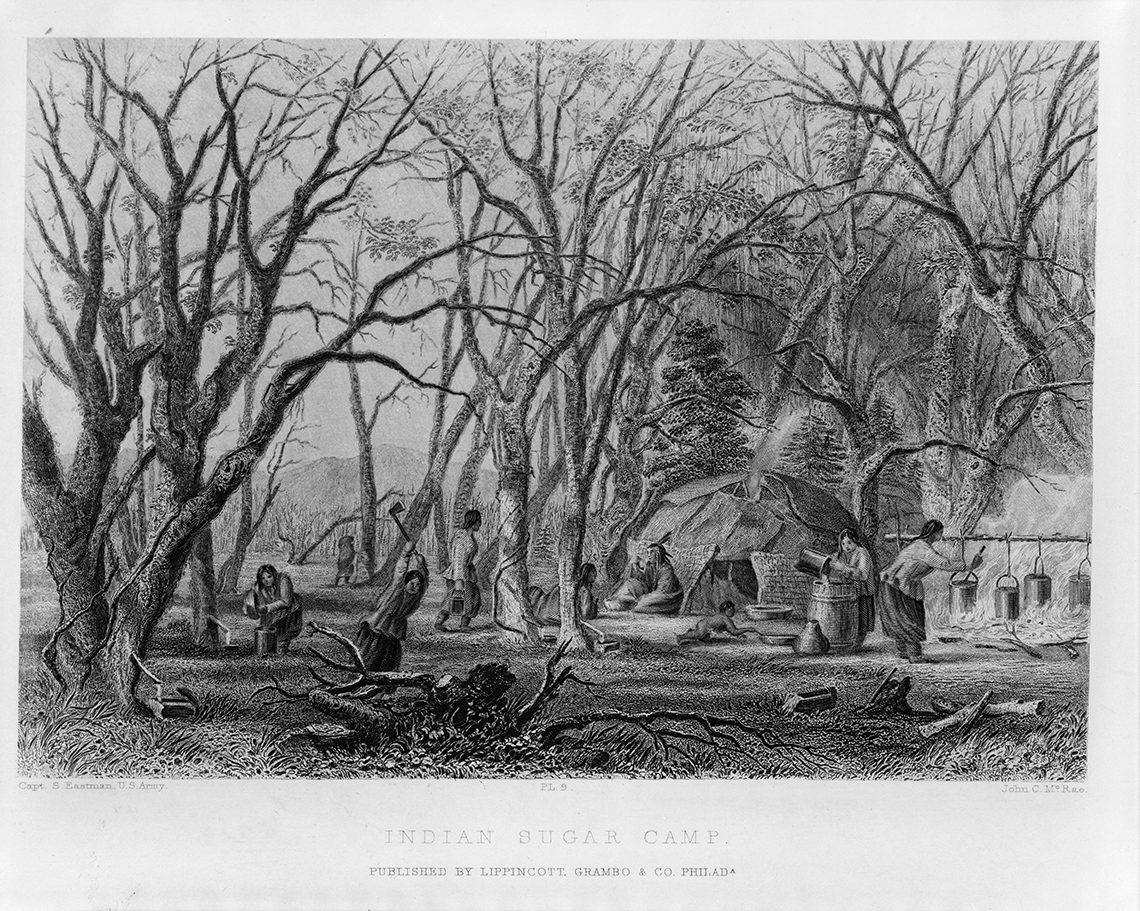 Anishinaabeg women making maple syrup at a sugar camp. There is a wigwam in the image as well.
