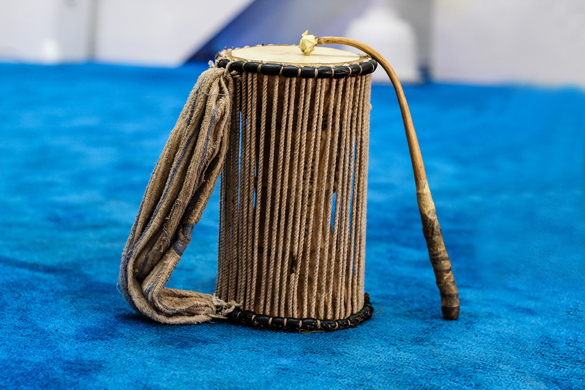 A Djembe, which is a small drum encased in a series of strings. There is also a striker mallet for playing the drum.