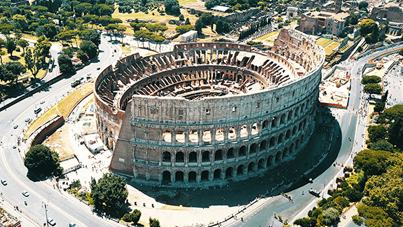 Aerial view of a circular building, the Colosseum, which has 4 levels of arches from the ground up.