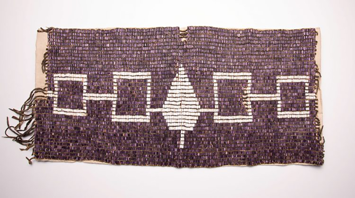 White beads on belt forms 5 symbols: small square, big square, tree, big square, and small square.