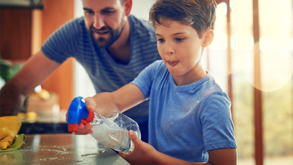 Kid and parent cleaning the countertop together as a chore.