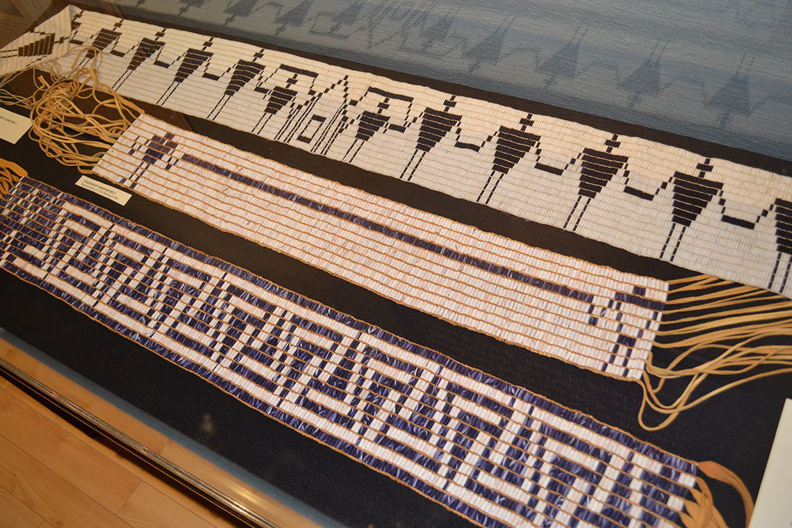 A wampum belt made by the Onondaga. It has a house with people joining hands on its sides.
