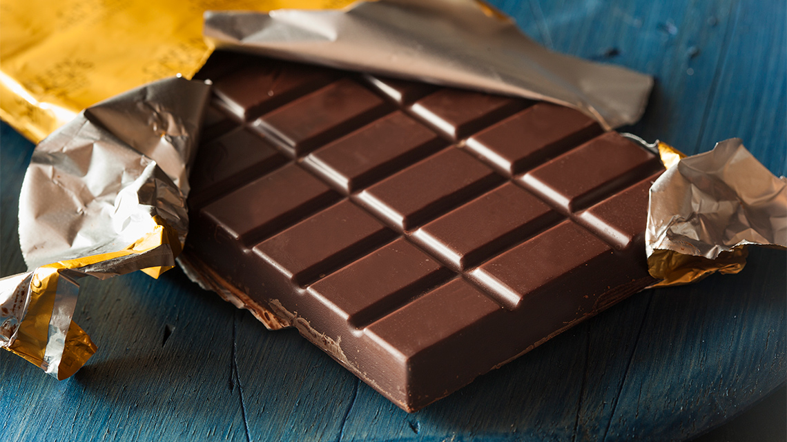 A hand holds up a chocolate bar.