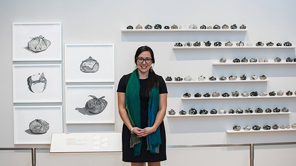 A image of Japanese Canadian artist Emma Nishimura in front of her drawings and sculptures