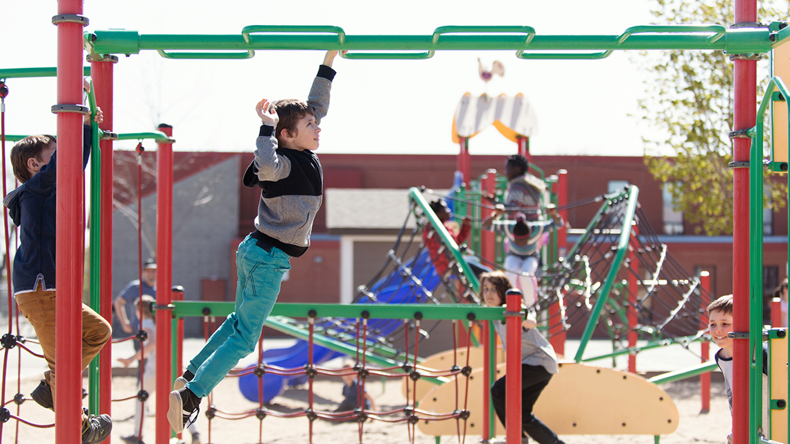 A playground with a climber, a few slides, lots of climbing areas, and a sandy ground.