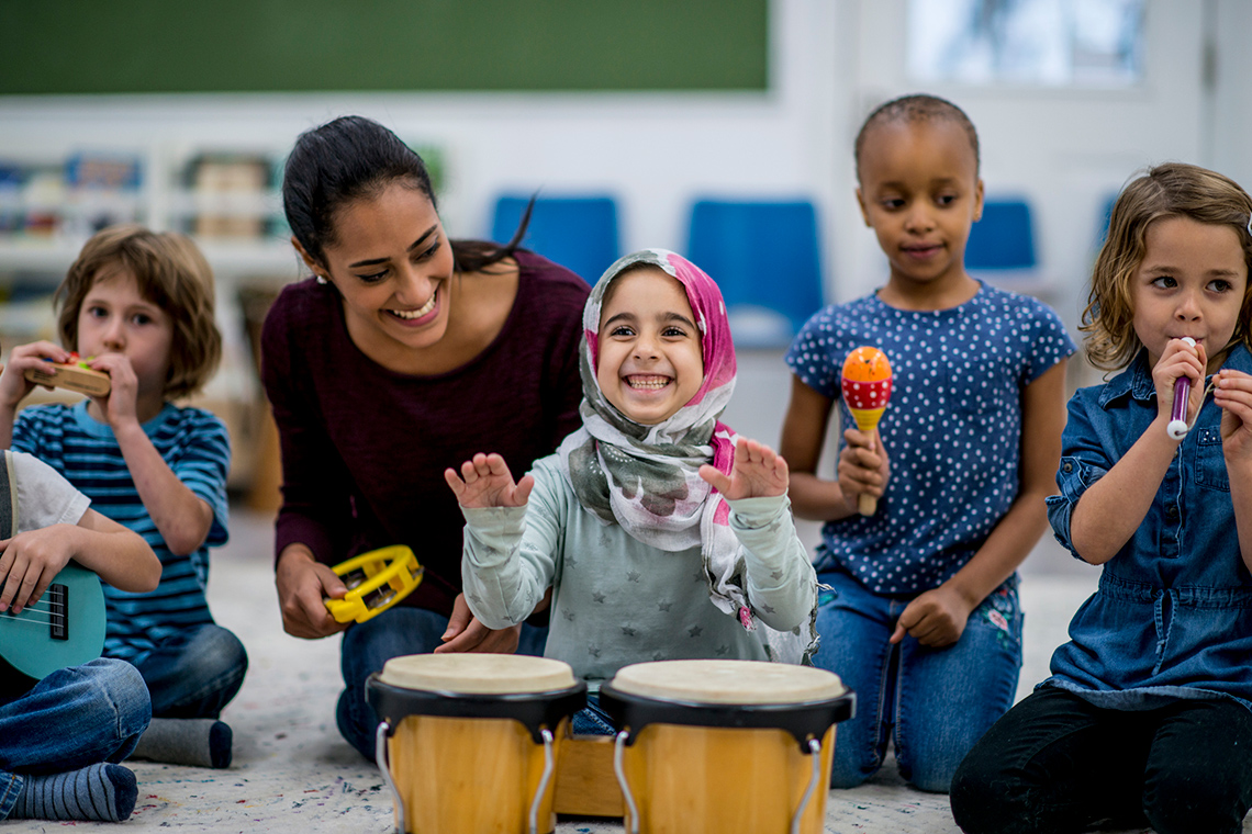 A community helper helping children play musical instruments like drums and maracas.