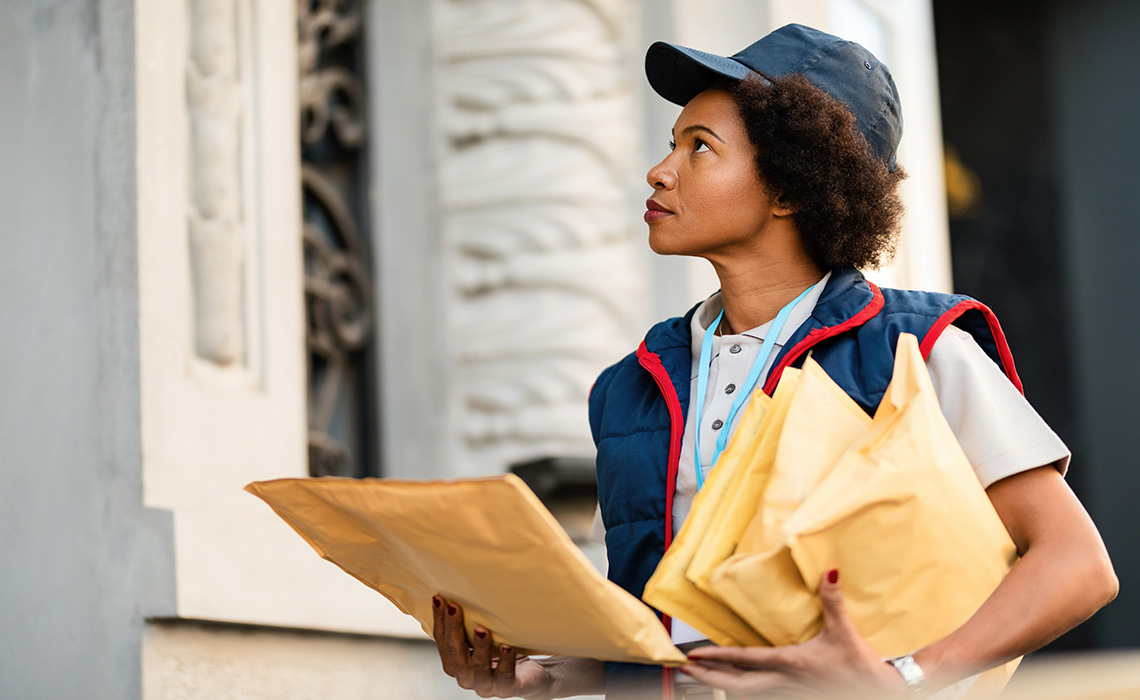 A mail carrier delivering packages. They are outside someone’s door.