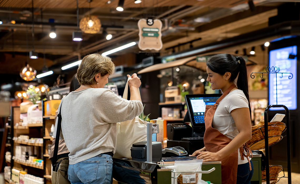 A grocery clerk is cashing out a customer.