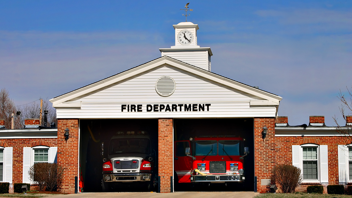 Two fire trucks are parked inside a fire station.