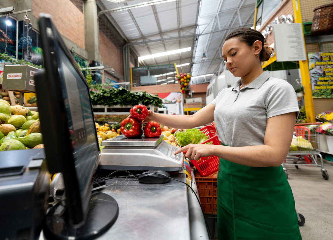 A grocery store worker weighing peppers.