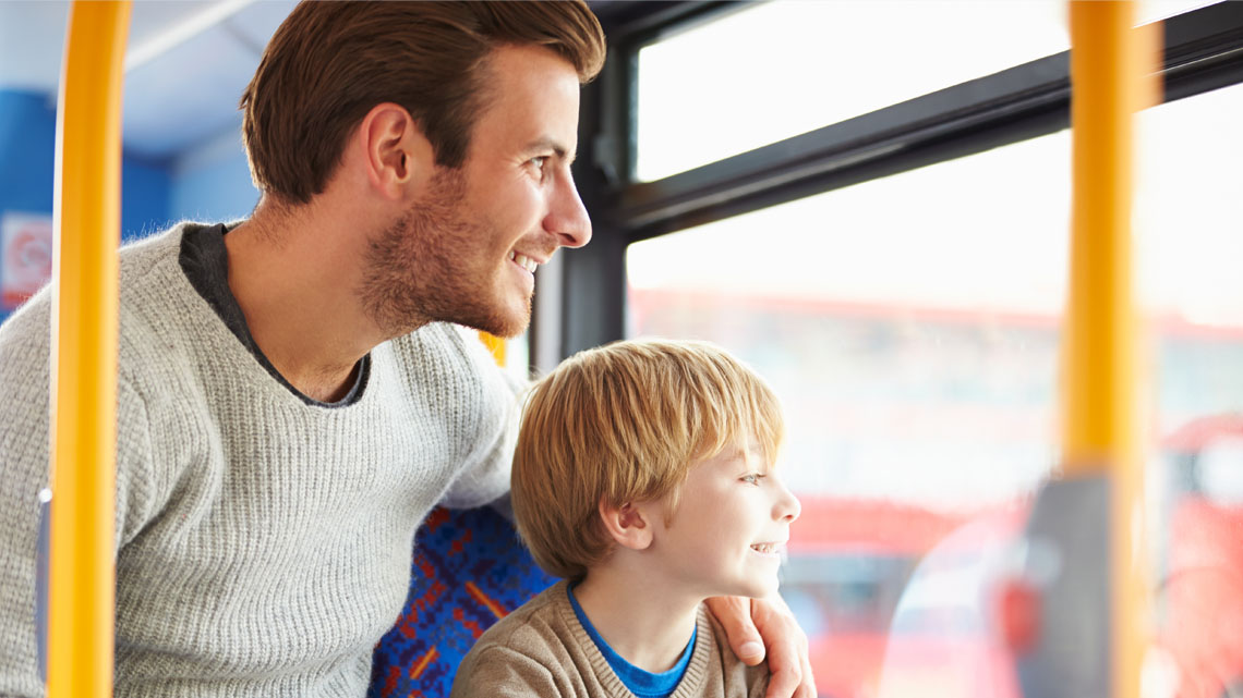 Parent and child sitting on a bus looking out the window.