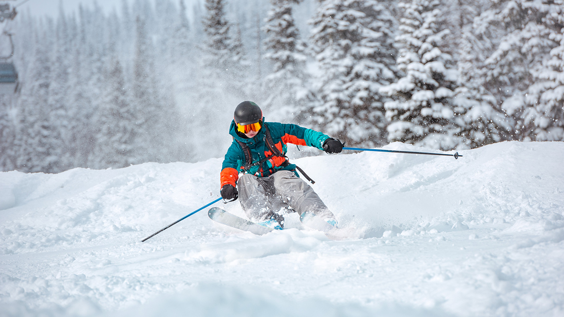 A person skiing downhill on fresh snow.