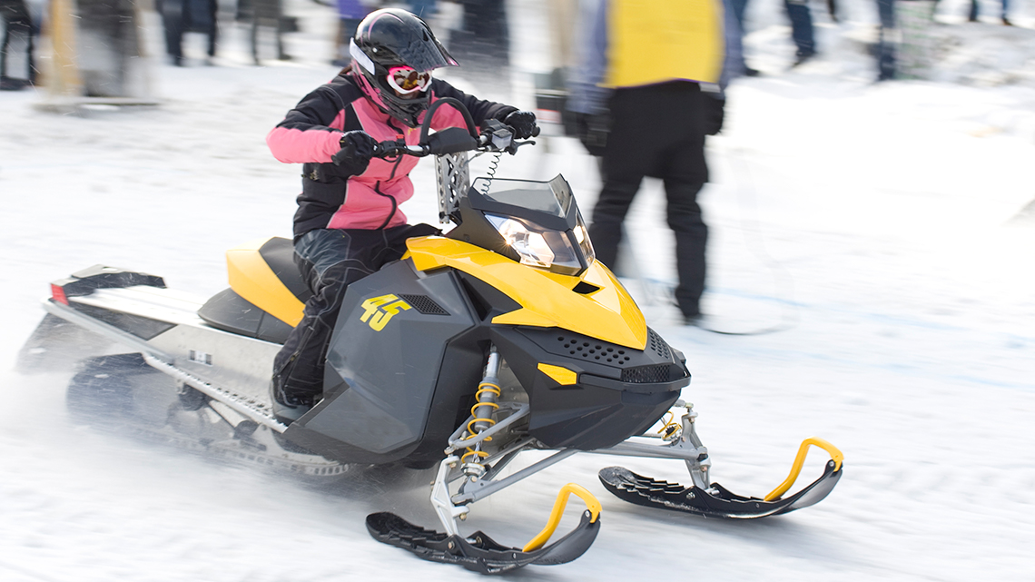 A person riding on a ski-doo snowmobile.