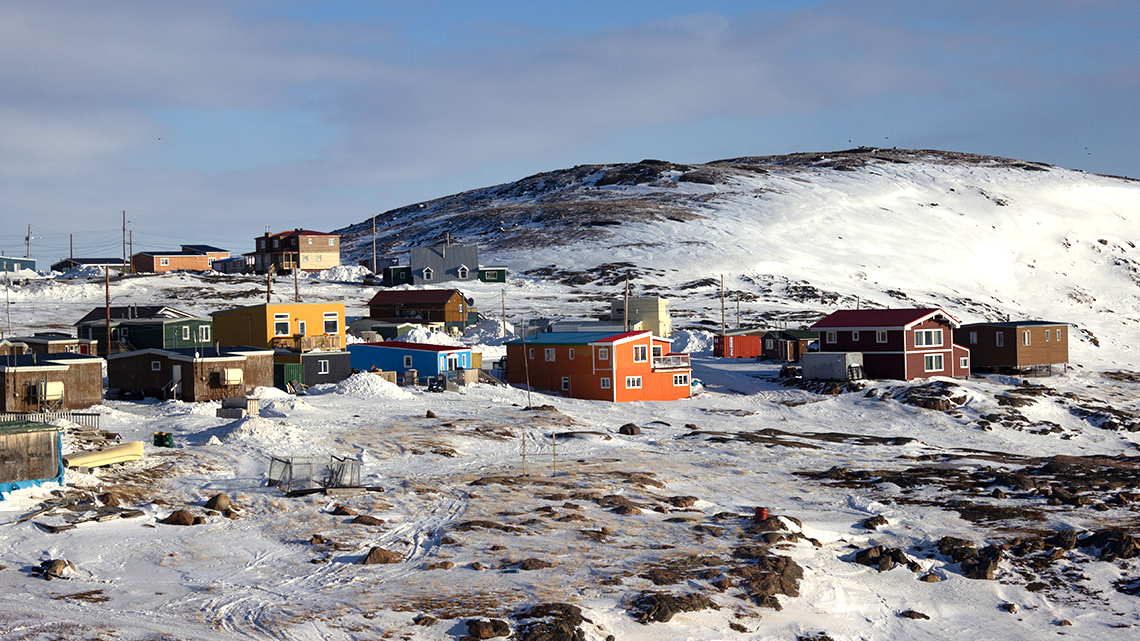 An image of Apex,Nunavut. There is a smal snow hill with many homes in front of it.