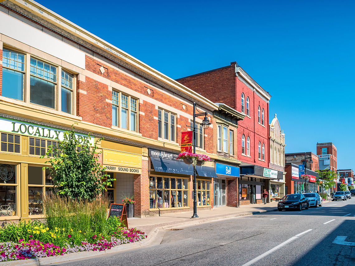 A row of small businesses and some parked cars in downtown Parry Sound Ontario – a small town.