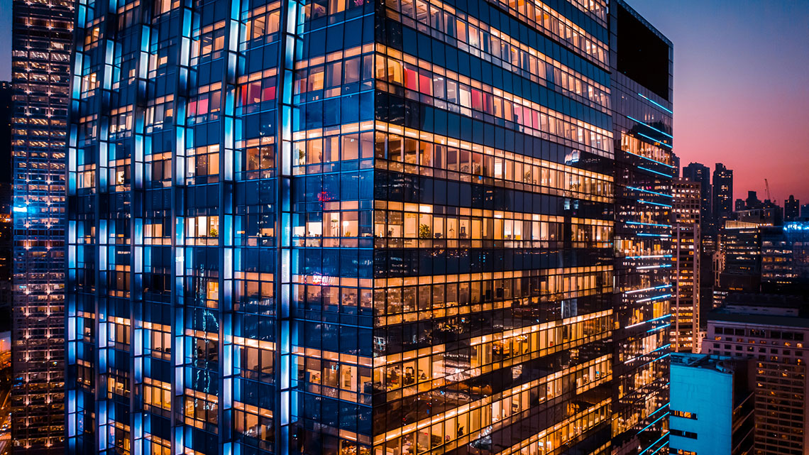 A tall office building at night with illuminated windows.