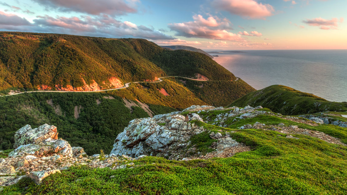 A trail on a forest covered hill with a coast in the background.