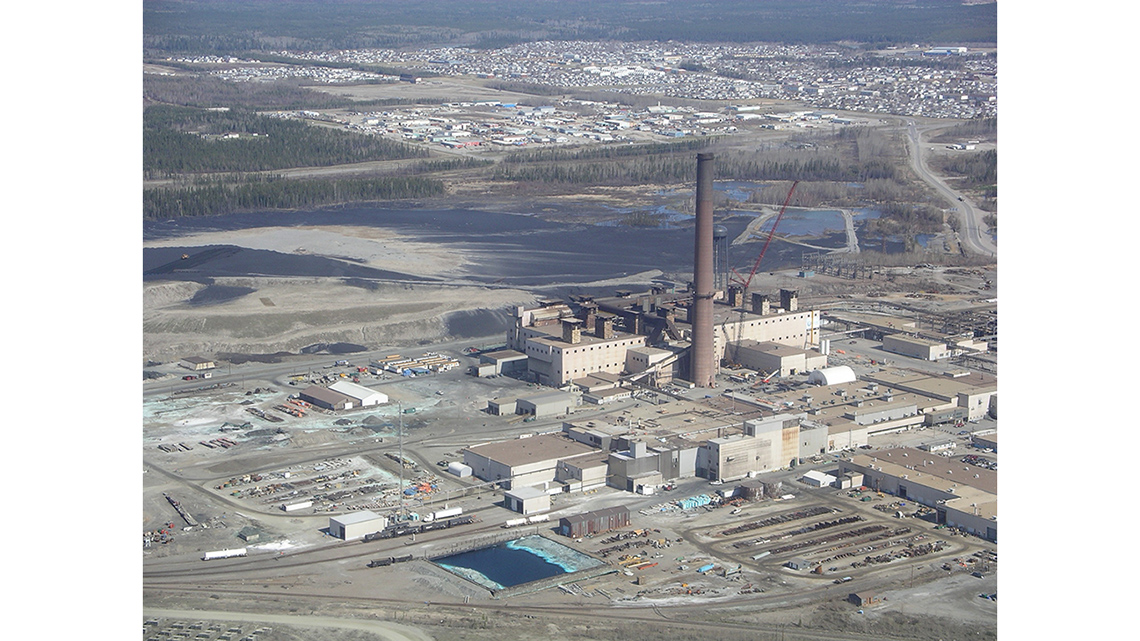 A large nickel mine with a city and forests in the background.